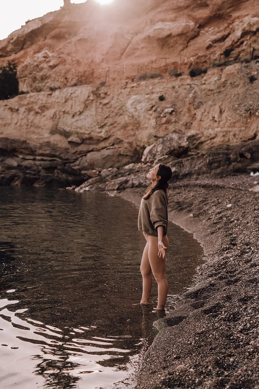 Een vrouw stapt de baai in, het water tot aan haar enkels