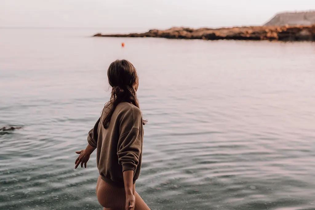 Een vrouw staat in zee met haar blik op de horizon