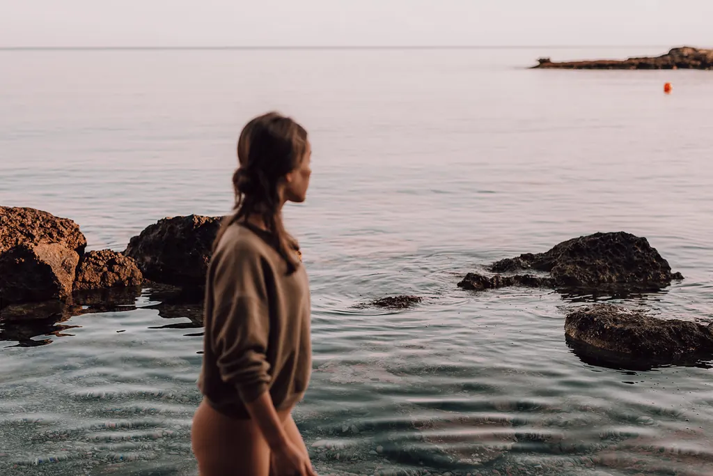 Een vrouw wandelt door het ondiepe zeewater tussen de rotsen