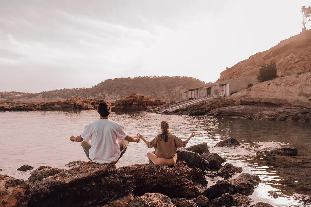 Meditatie op de rotsen aan zee, de handen rustend op de knieën