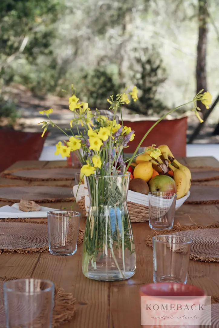 Een gedekte tafel met gele bloemen en een schaal fruit