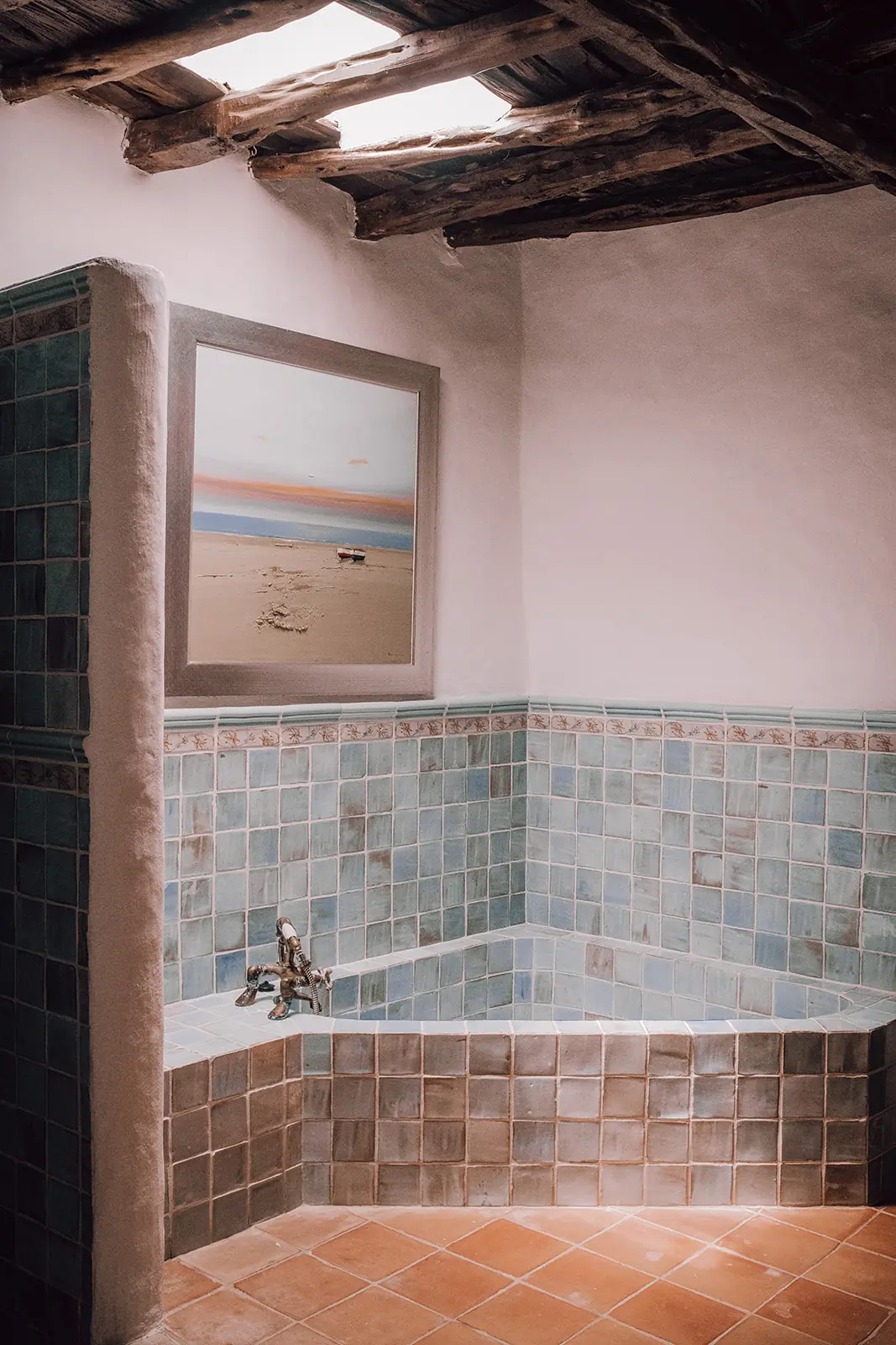 Een badkamer met blauwgroene tegels en een ingemetseld bad
