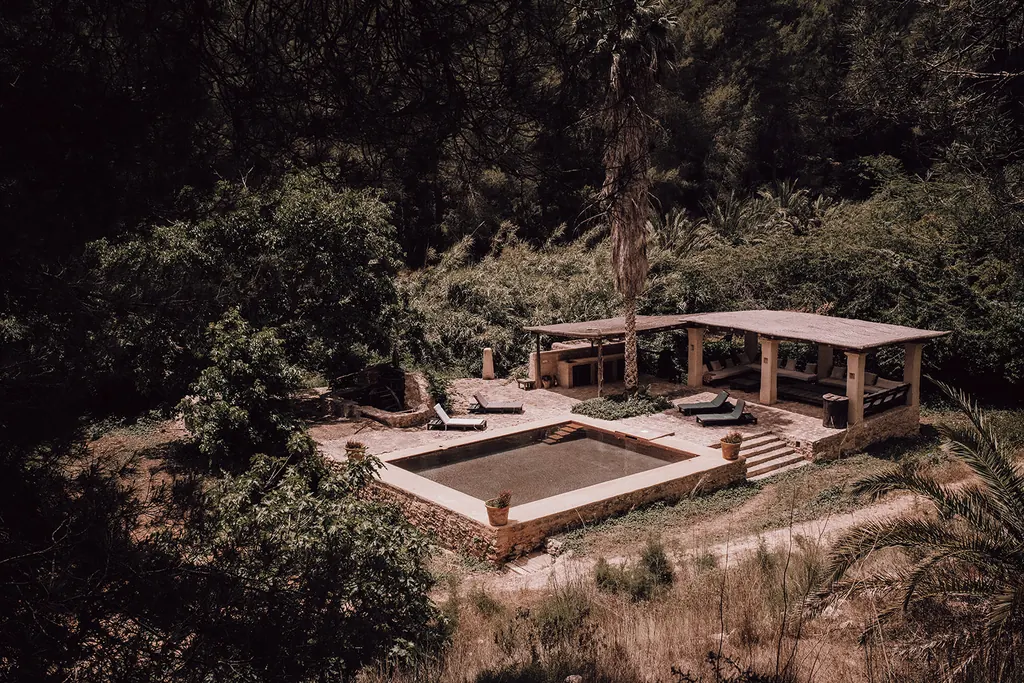 Een verzonken bad met een houten pergola tussen het groen
