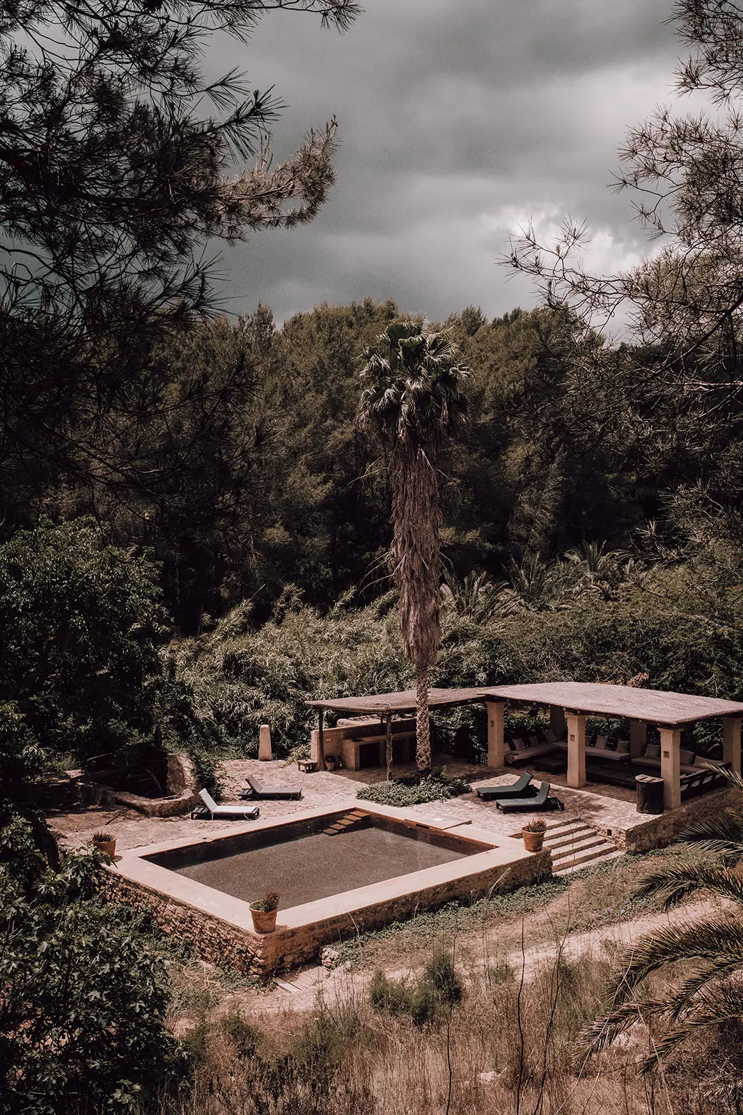 Het verzonken bad met de pergola onder een donkere wolkenlucht