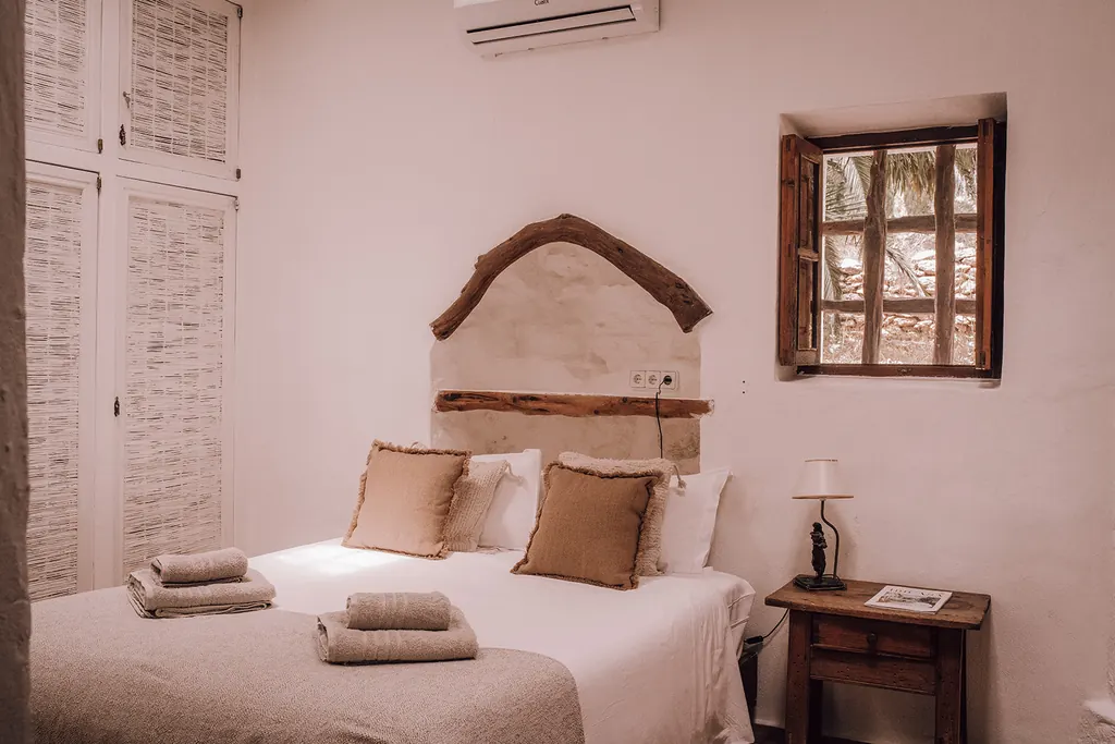 Een lichte slaapkamer met een tweepersoonsbed en een klein raam