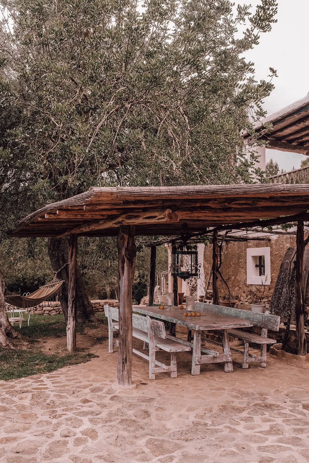 Een lange houten tafel onder een pergola in de tuin