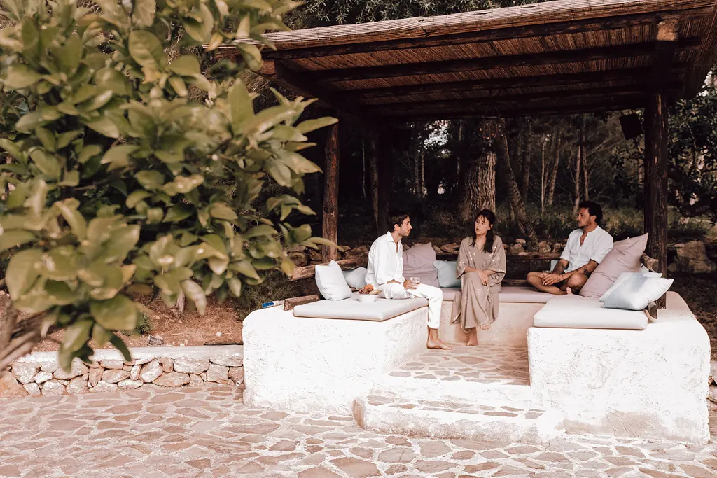 De witte lounge onder de pergola, half verscholen achter het groen