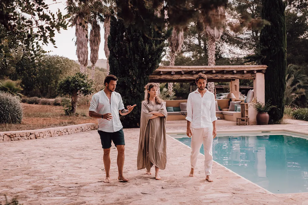 Drie mensen wandelen langs het zwembad van de finca