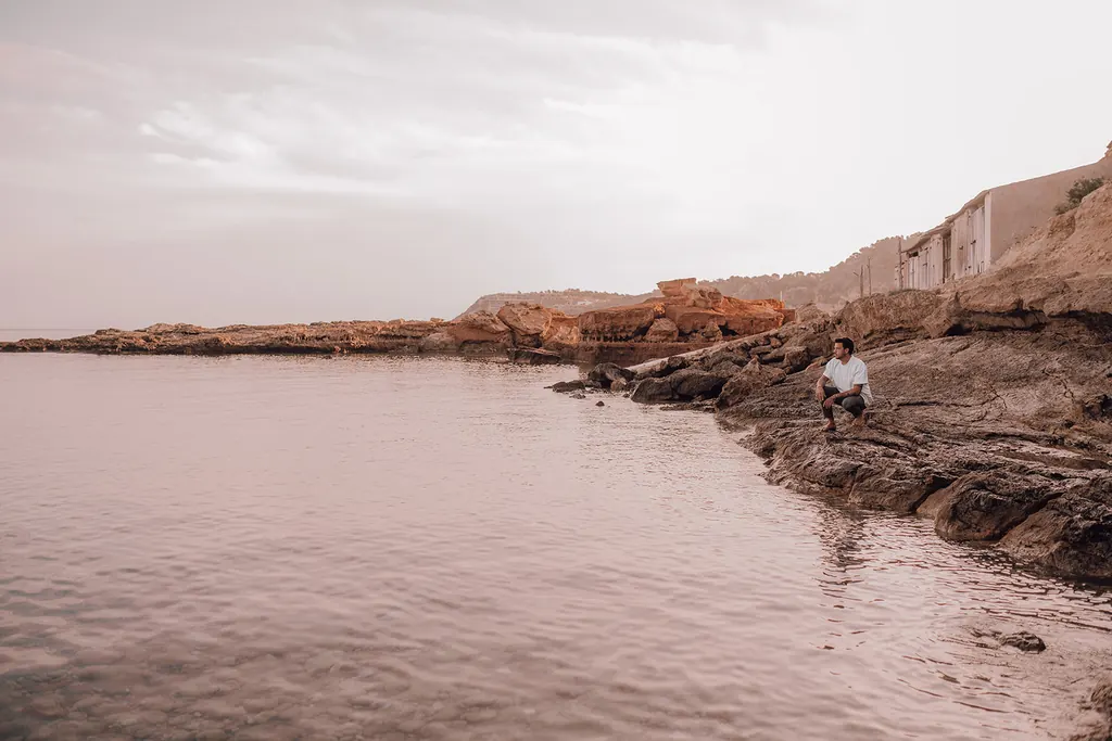 Een stille baai in de ochtend met iemand die op de rotsen zit