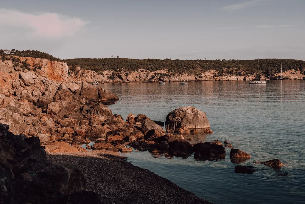 Rode rotsen en zeilboten in een rustige baai op Ibiza