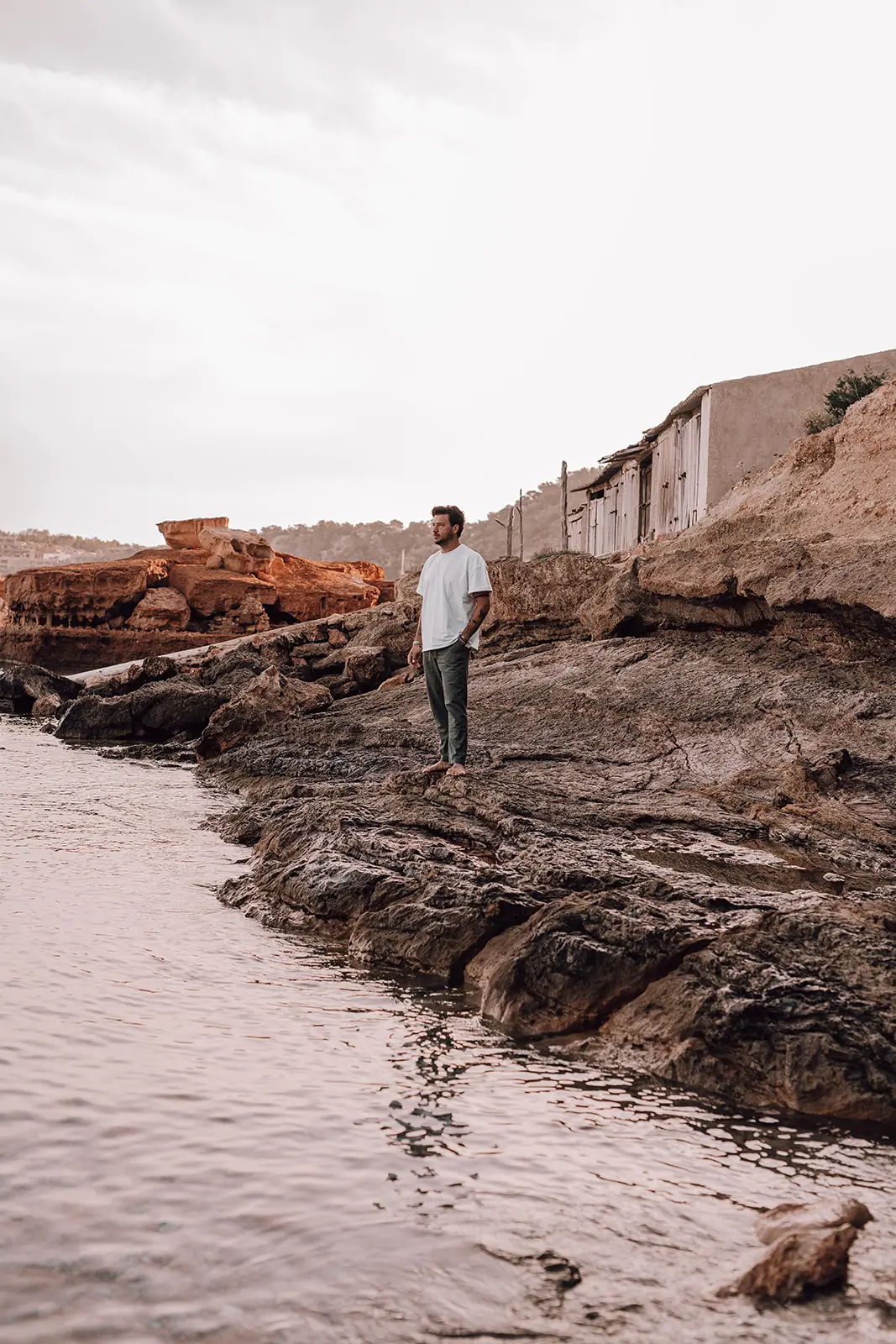 Rocco staat op de rotsen bij de vissershuisjes in de baai